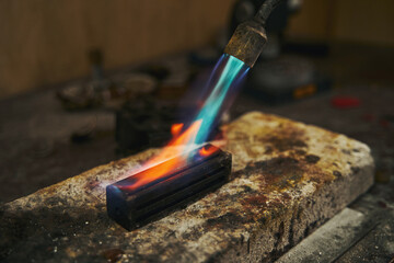 Craftsman is smelting metal with soldering torch