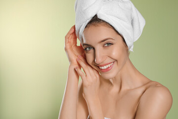 Wall Mural - Beautiful young woman with hair wrapped in towel after washing on light green background