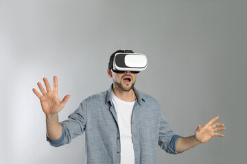 Wall Mural - Man using virtual reality headset on grey background