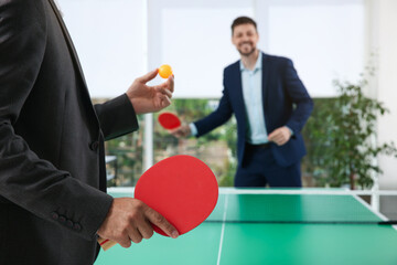 Wall Mural - Business people playing ping pong in office, focus on tennis racket