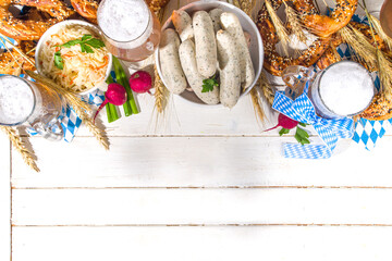 Wall Mural - Oktoberfest food background, Traditional bavarian holiday food menu, sausages with pretzels, sauerkraut, beer glass and mugs on white wooden sun lighted background copy space