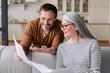 © InsideCreativeHouse - Happy mature couple checking documents, middle-aged family celebrating success,paying domestic bills, planning budget, adoption documents, mortgage.