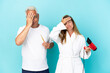 Middle age couple holding dryer and toothbrush isolated on blue background with surprise and shocked facial expression