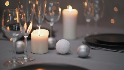 Wall Mural - Festive served dining table. Beautiful dishes, tablecloths, wine glasses and gray plates. Candles and a garland in the background. Minimalistic dining room decor. Christmas dinner.