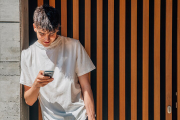 Canvas Print - teenage boy looking at mobile phone on the street