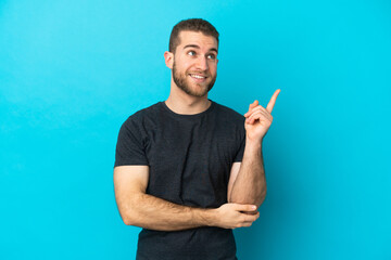 Young handsome caucasian man isolated on blue background pointing up a great idea