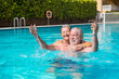 © Daniel - Couple of two happy seniors having fun and enjoying together in the swimming pool smiling and playing. Happy people enjoying summer outdoor in the water