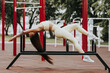 © Виталий Сова - Sporty woman with long straight hair, dressed in sportswear, trains in a city park, stretching leg exercise