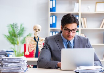 Businessman working with skeleton in office