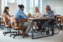 Group Of Business People In A Meeting With Colleague In A Wheelchair For Inclusion. Happy Mature Businessman On Wheelchair With Colleagues In Office.