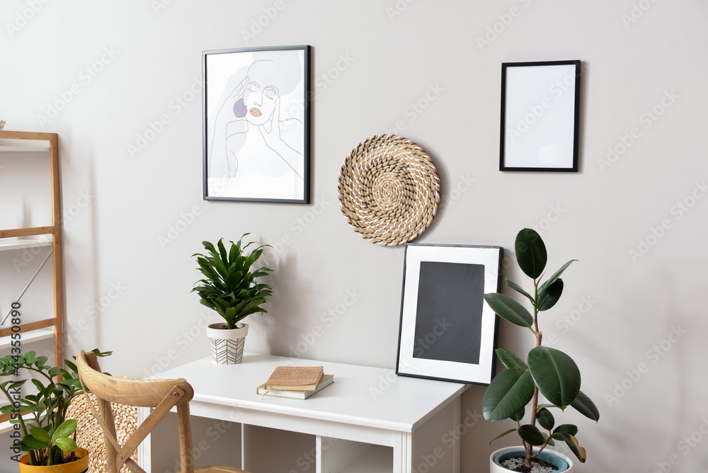 Modern workplace with frames near light wall