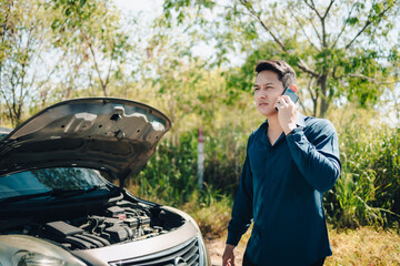 Wall Mural - young man calling,  texting for car service on roadside assistance after broken car. Car broken, car breakdown concept.