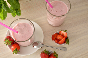 Wall Mural - Two glasses of strawberry milkshake on wooden table elevated