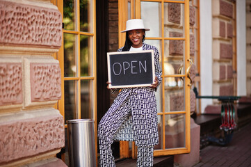 African american woman hold open welcome sign board in modern cafe coffee shop ready to service, restaurant, retail store, small business owner.