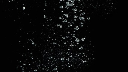 Wall Mural - Soda water bubbles splashing underwater and floating water drop in black background. Motion picture footage. represent sparkling and refreshing of carbonate drink such as cola or soda. Bubbles macro.