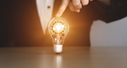 man pointing to the light bulb and there is a gear icon in it. inspiring online technology concept. innovation concept