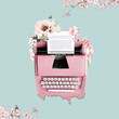 Pink typewriter decorated with flowers on a green background