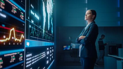 Fototapete - Young Female Computer Science Engineer Looking at Big Screen Display Showing Global Map with Data Points. Telecommunications Technology Company System Control and Monitoring Room with Servers.