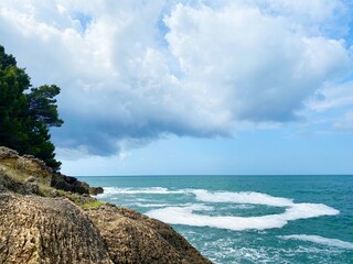 Canvas Print - Mediterranean rocky coast beautiful landscape in stormy  weather. Cloudy sky over blue sea. Pine trees on rocky seashore. Scenic Mediterranean nature. Summer in Montenegro.