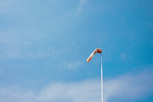 Red White Striped Wind Sock In Front Of Blue Sky