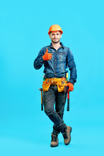 Full Length Portrait Of Confident Handsome Male Construction Worker In Safety Helmet Showing Thumbs Up Sign