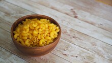 Uncooked Dry Macaroni Pasta In A Wooden Bow On A Rustic Wooden Table.
