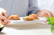 © larionovao - Young girl holds tray with fresh salmon and avocado on white bread.