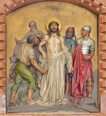 Canvas Print - VIENNA, AUSTIRA - JUNI 18, 2021: The relief of  Jesus clothes are taken away (part of Cross way) in the Herz Jesu church from begin of 20. cent. by Workroom from Munich.