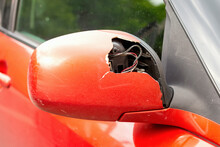 Selective Focus Of A Broken Red Car Mirror With Wires Sticking Out And A Control Unit In A Hole In The Plastic Cover. The Concept Of Auto Insurance. Repair Of The Car After The Accident.