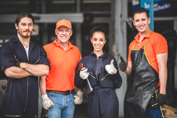 a portrait group photo of machanic team smilling in front of garage with thumb up, the professional engineer colleague in uniform, teamwork concept.