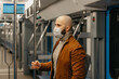 © Roman Tyukin - A man with a beard in a medical face mask to avoid the spread of coronavirus is standing and holding the handrail in a subway car. A bald guy in a surgical mask is keeping social distance on a train.