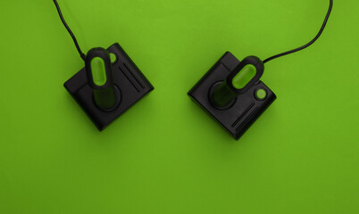 Canvas Print - Retro joysticks on green background. Gaming, video game competition. Top view