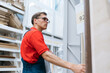 © yurolaitsalbert - employee of a flooring store standing near the shelves with a laminated board.