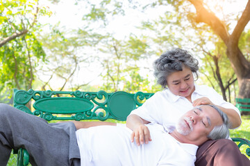 Wall Mural - Elderly couple resting on bench in a park Happy old couple smiling in a park on a sunny day Old wife look at old husband with love during older grandfather sleeping and take a rest Retirement concept 