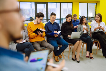 Wall Mural - Group of business people meeting in a seminar conference. Audience listening to instructor and making notes. Student training, lecture. Planning, education, analysis, collaborate work in teamwork.