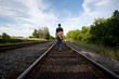 © IntoIt - Young Man with Guitar slung on Back walking down Rail Road tracks