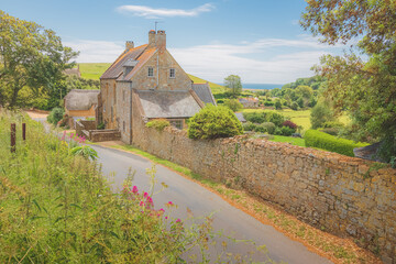 Wall Mural - Traditional stone cottage farmhouse on a country lane in the quaint charming rural English village of Abbotsbury, Dorset, England, UK.