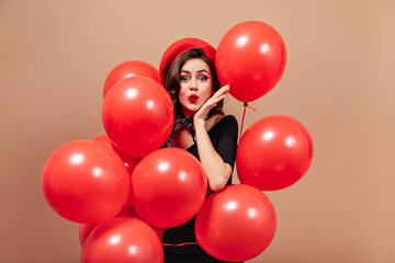 Sticker - Elegant girl in red beret and black dress blows kiss and holds huge balloons