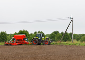 A tractor with a sowing complex processes agricultural land.