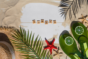 The concept of a holiday at the sea. Seashells, stars, a straw hat, bikinis, sunglasses, lime flip-flops and maracas on the sand. Background for summer holidays with space for text. Top view.