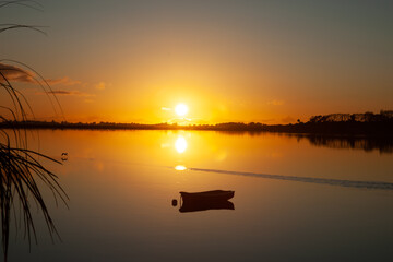 Poster - Sunrise across bay with golden glow and moored dinghy