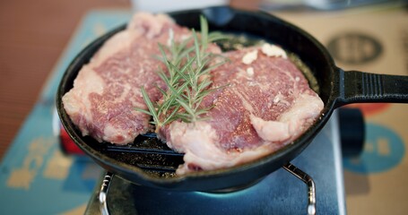 Poster - juicy fresh raw meat beef BBQ steak roasting grilling on hot iron pan with rosemary on top, cooking food lifestyle eating