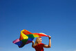 © Aleksandra Iarosh - girl with lgbt flag behind her back against a bright blue sky
