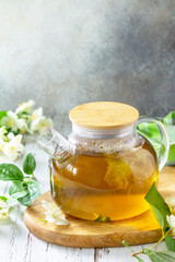 Wall Mural - Therapeutic herbal tea. Hot Jasmine tea with jasmine flowers in a glass teapot on a rustic wooden table. Copy space.