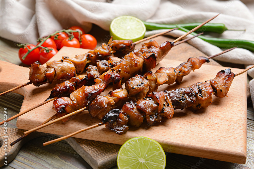 Board with tasty chicken kebab on wooden background