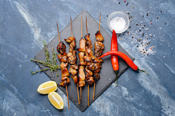 Board with tasty chicken kebab on color background