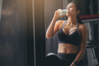 Happiness woman in sportswear drinking protein powder milkshake after workout at fitness gym.