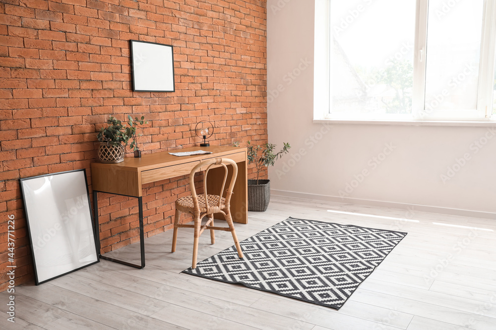 Interior of modern room with comfortable workplace and blank photo frames