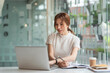 © amnaj - Beautiful Asian woman working with laptop and taking notes at the office.