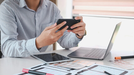 close-up of man designer holding smartphone to develop ux ui at office.